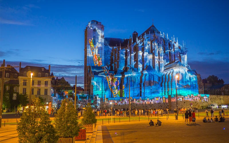 Illumination spectaculaire de la majestueuse Cathédrale Saint-Julien au Mans lors de la Nuit des Chimères, une nuit magique où histoire et féérie se rencontrent à travers des projections artistiques et colorées.